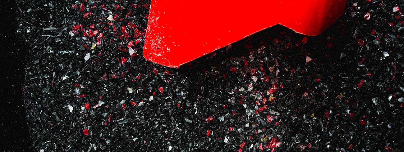 zenith-records-sustainability-header-003 an image of black and red crushed vinyl, with a red shovel on top